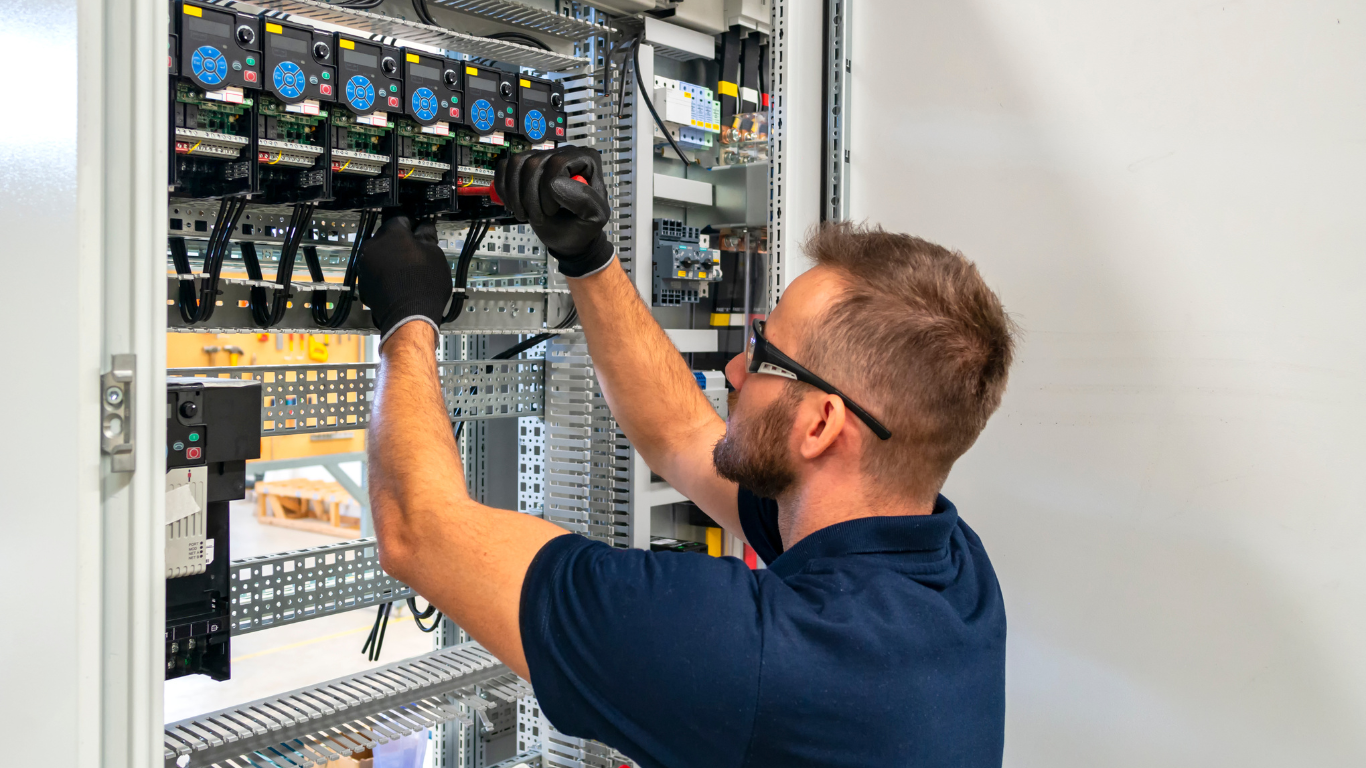 A man is working on an electrical box in a factory.