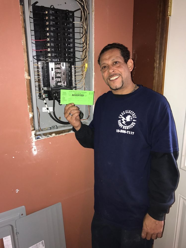 A man in a blue shirt is standing in front of an electrical box holding a green card.