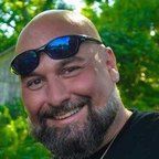 A woman is sitting at a desk with a laptop and a vase of flowers.