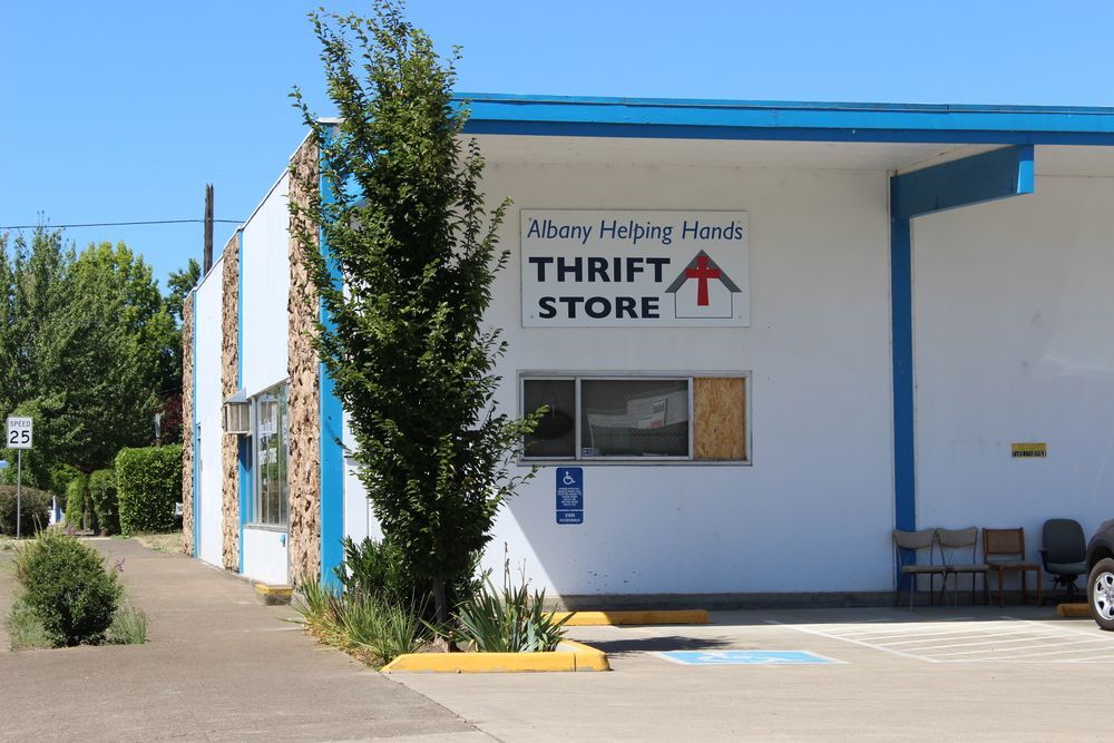 A white building with a blue roof and a sign that says thrift store