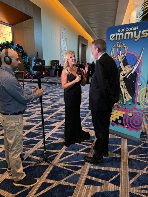 Sandra Peebles in a black gown interviews a man in a suit.