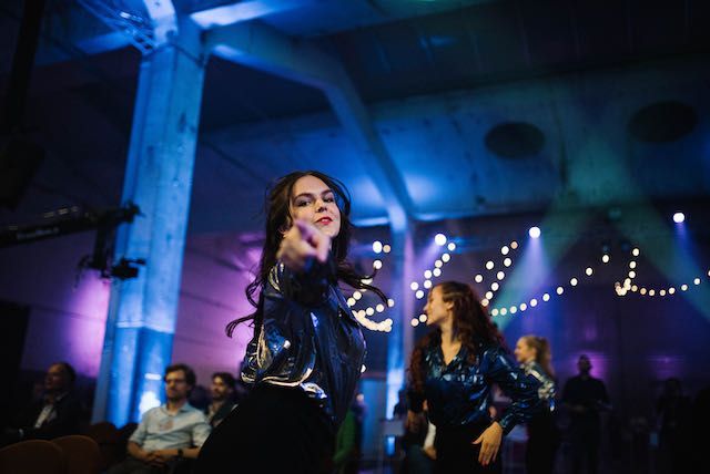 Een vrouw in een glinsterend topje danst met anderen op een feest met blauwe en witte lichten.