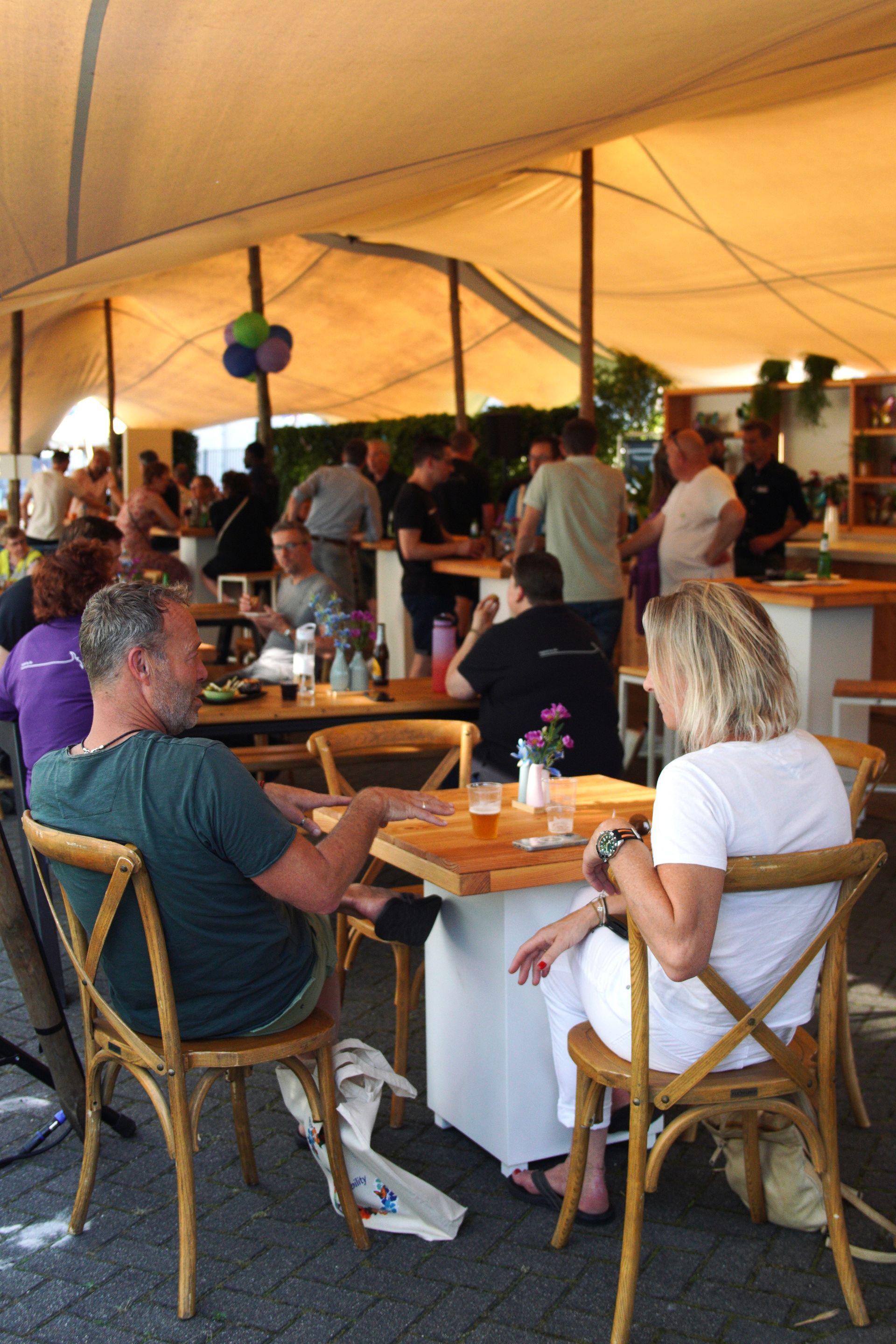 Bezoekers en relaties genieten op het terras onder de stretchtent tijdens het Life & Mobility Open Dagen evenement, professioneel verzorgd door Plan X Events.