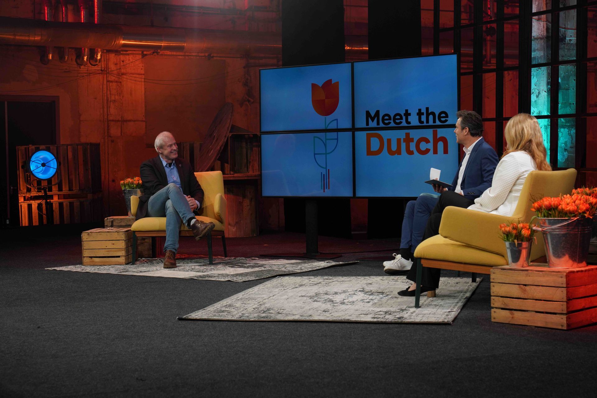 Televisiestudioset: drie personen zitten voor een