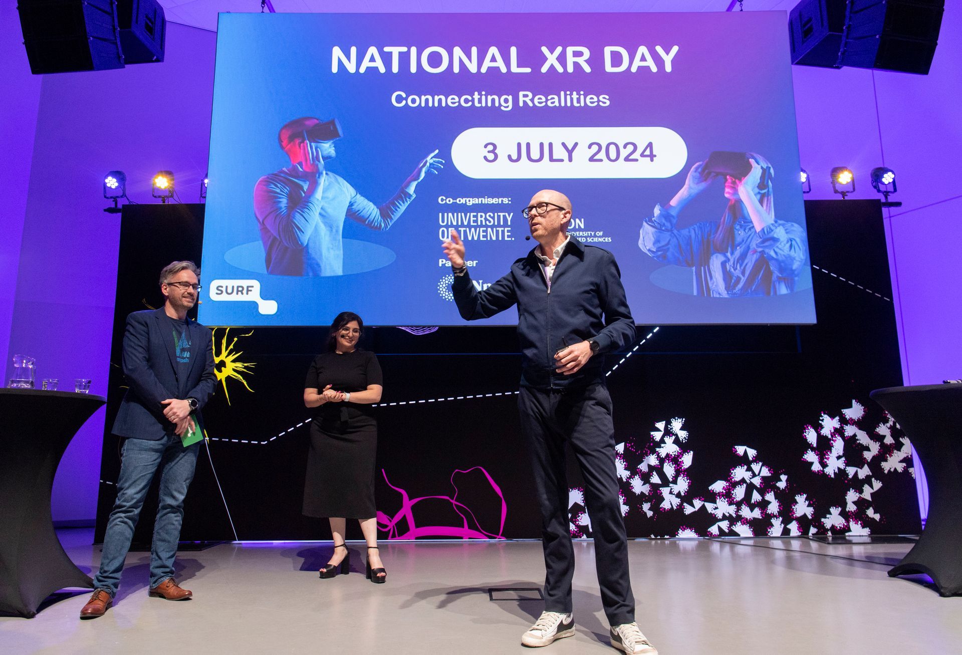 Spreker op het podium tijdens National XR Day aan de Universiteit Twente, deel van een inspirerend programma over XR-technologie, verzorgd door Plan X Events.