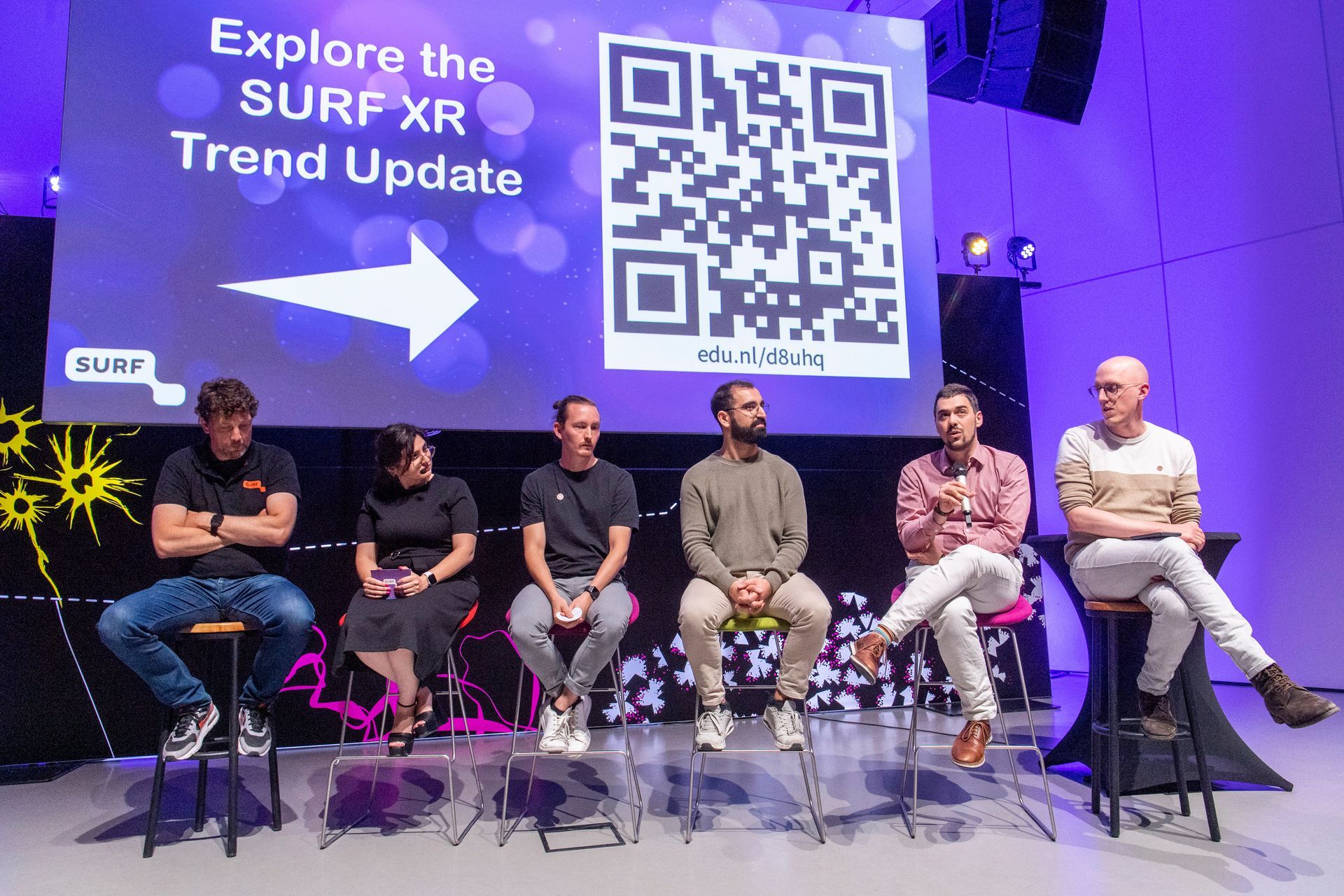 Sprekers presenteren op het podium tijdens National XR Day aan de Universiteit Twente, een kennisevent over Extended Reality, georganiseerd door Plan X Events voor 400 bezoekers.