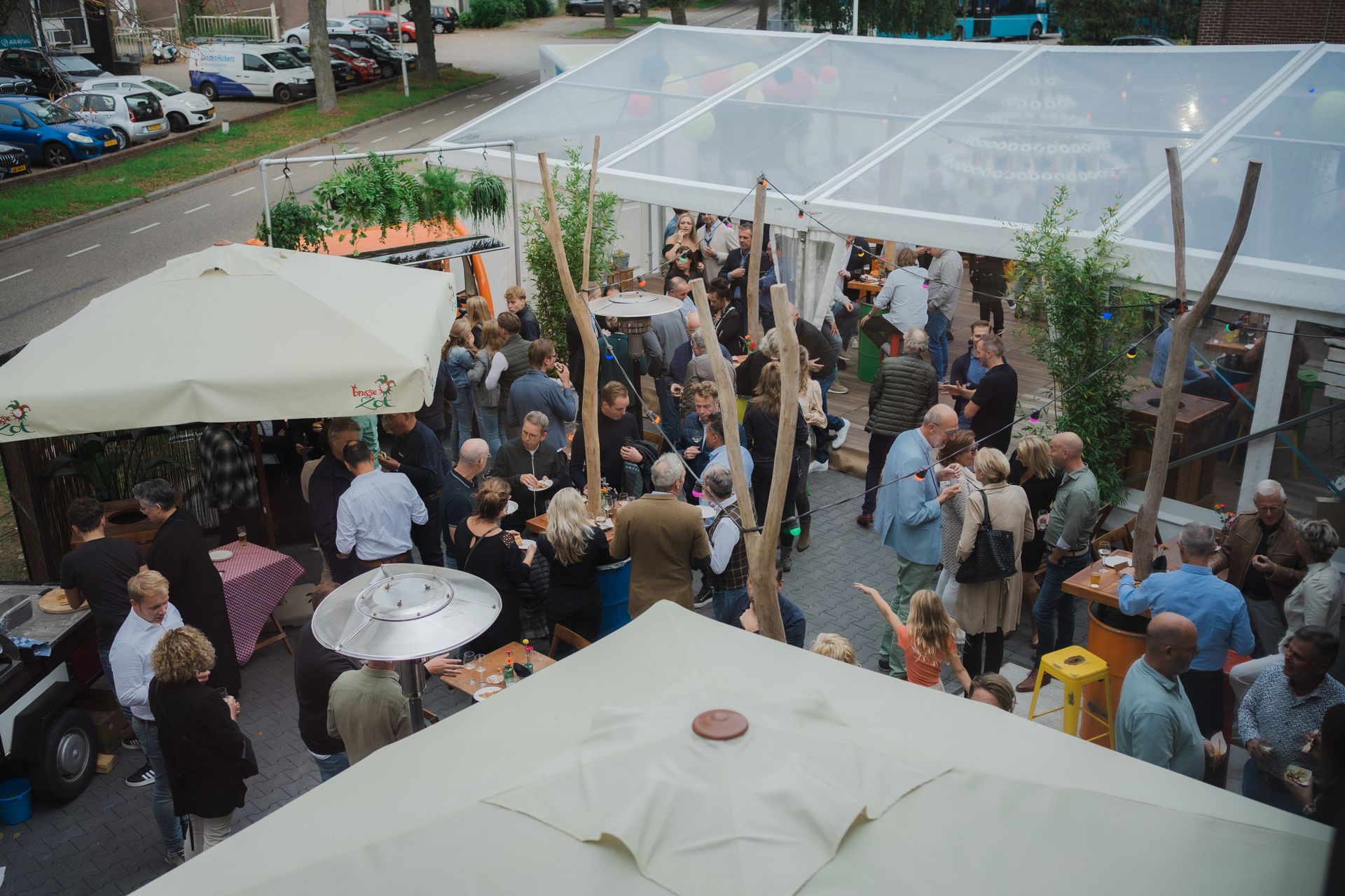 Groep gasten socialiseert in een tent tijdens de Open Bedrijvendag op een van de bedrijventerreinen in Doetinchem, een evenement dat verbinding en trots op lokaal ondernemerschap creëert, georganiseerd door Plan X Events.