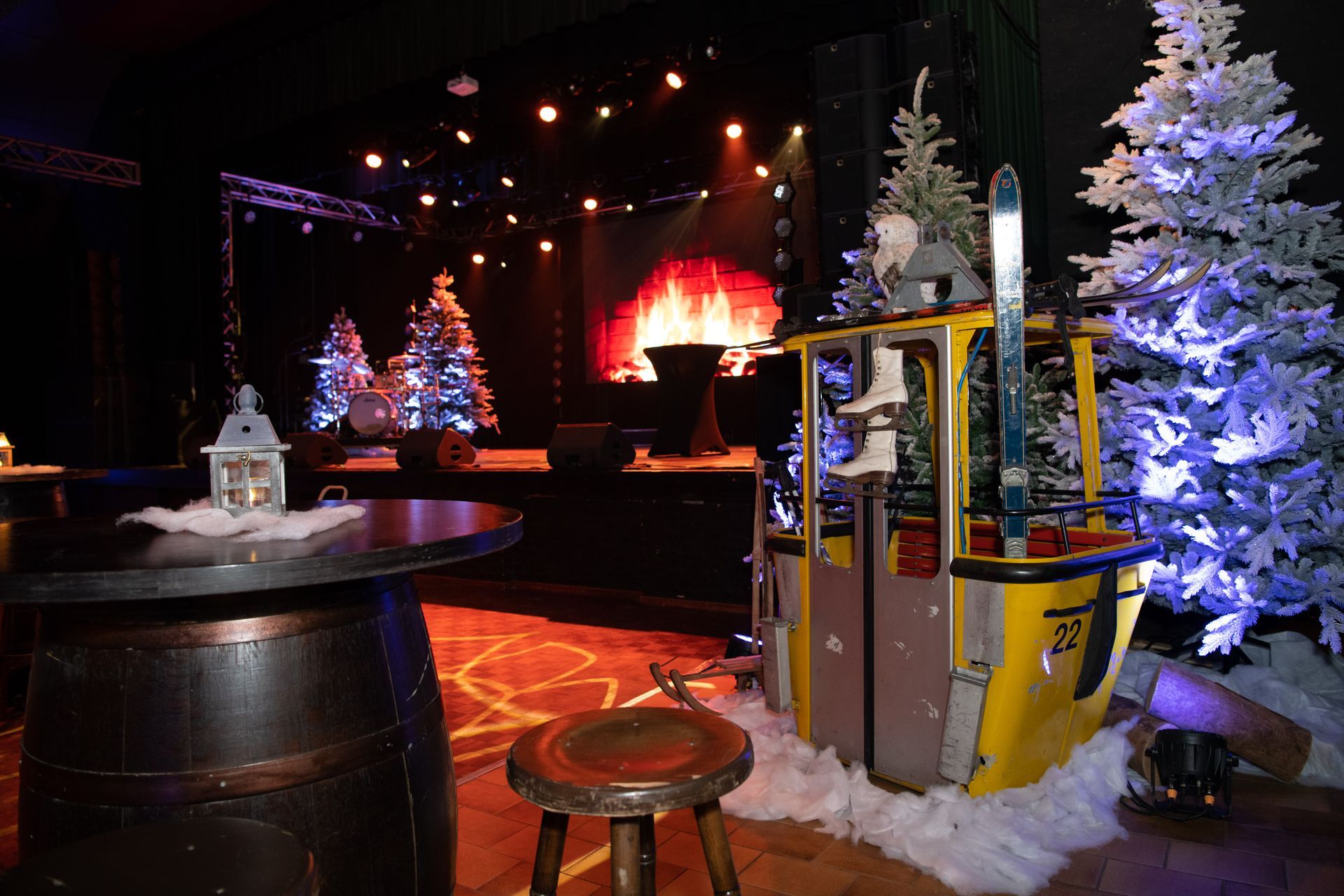 Evenement met skihutthema. Podium met nep-open haard, skilift, kerstbomen en zitplaatsen; sfeervol verlicht en met een feestelijke sfeer.