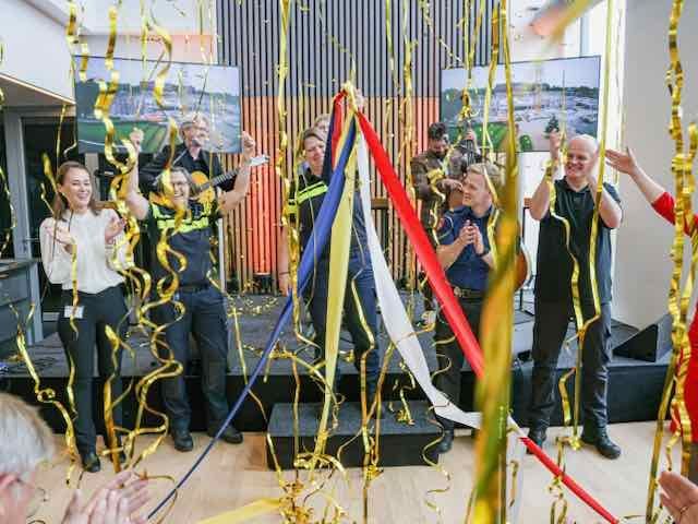 Confetti vult de ruimte terwijl politiemedewerkers juichen tijdens de feestelijke officiële opening van de nieuwe meldkamer Oost-Nederland in Apeldoorn, een ceremonieel moment dat de samenwerking tussen de hulpdiensten benadrukt en werd georganiseerd door Plan X Events.