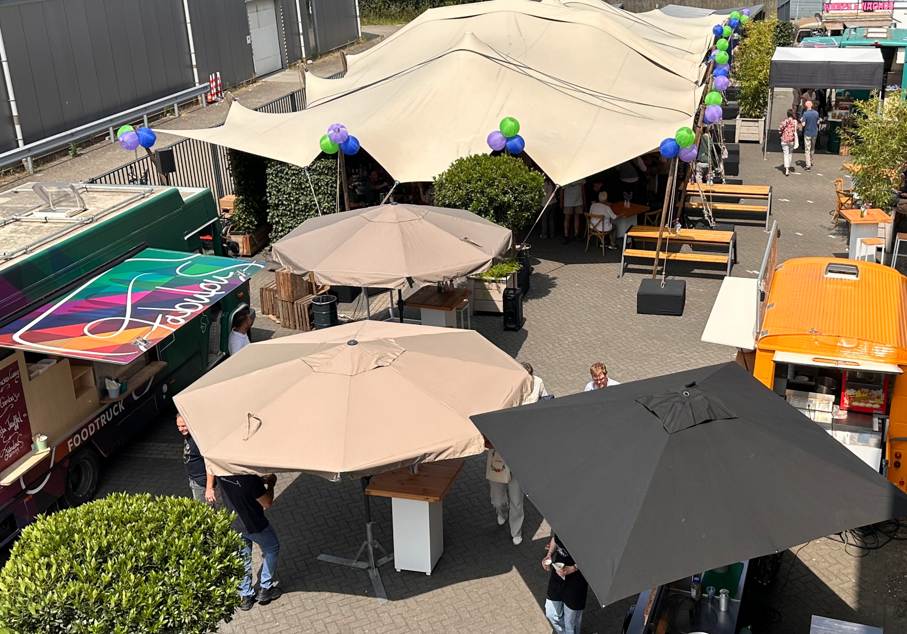 Foodtrucks en tafels met parasols op een openluchtmarkt.
