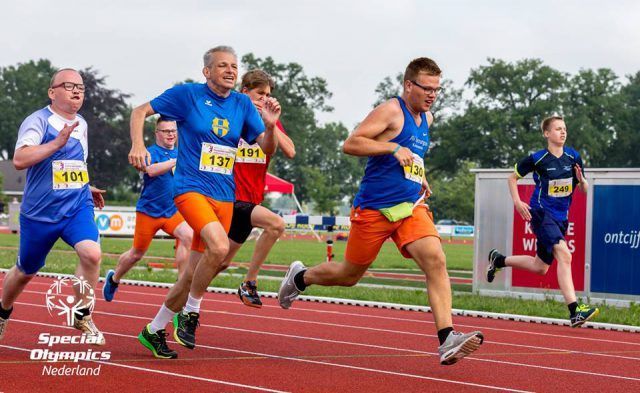 Tijdens Special Olympics Nederland strijden hardlopers in het blauw en oranje op een baan.