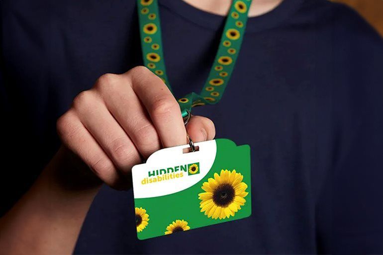 Persoon met een identiteitskaart met een zonnebloemmotief en een groen koord.