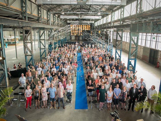 Groepsfoto van alle 350 gasten genomen van bovenaf met confetti, tijdens het jubileum van Waterschap Rijn en IJssel, een feest vol verbinding en trots, verzorgd door Plan X Events.