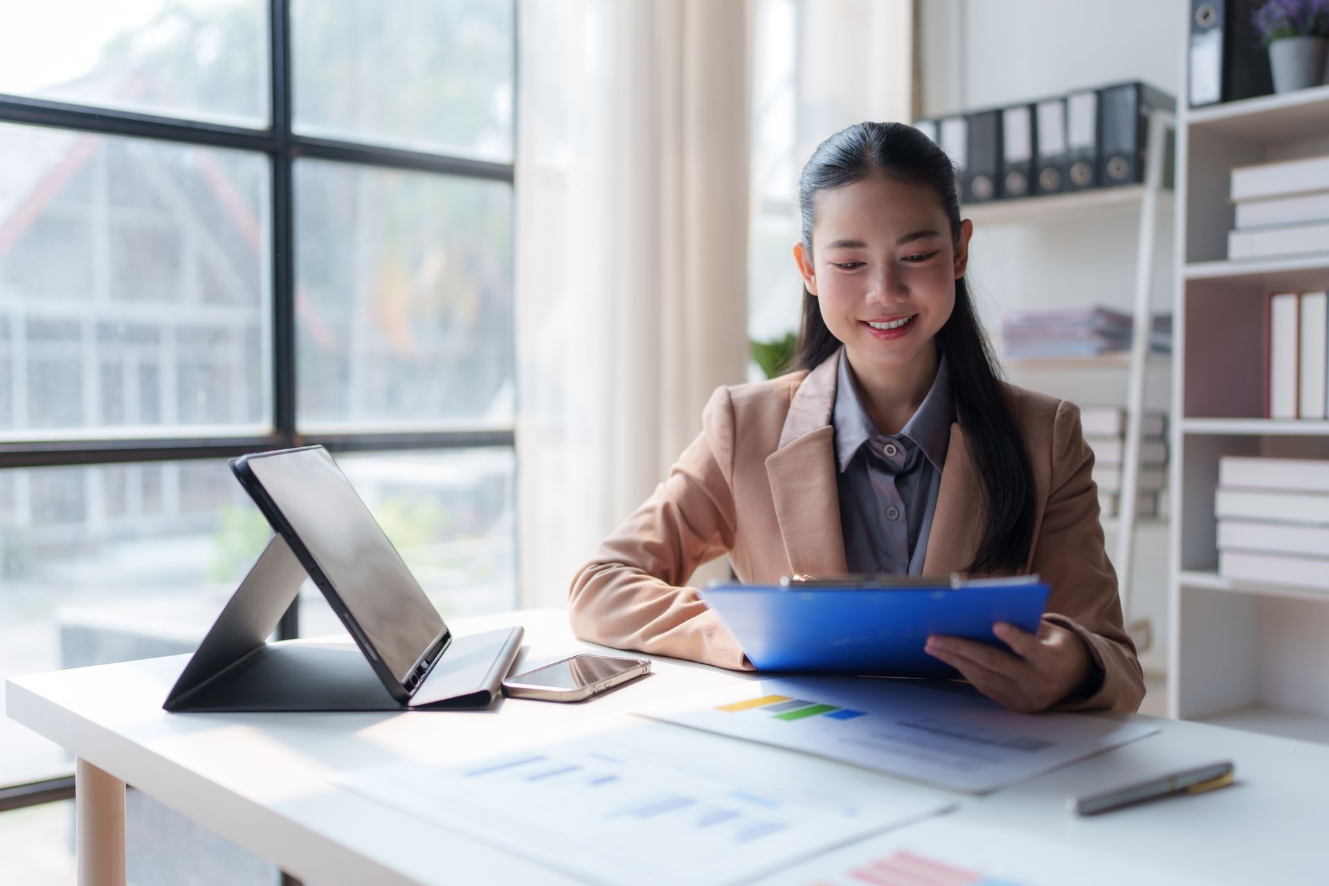 Une femme est assise à un bureau et regarde une tablette.
