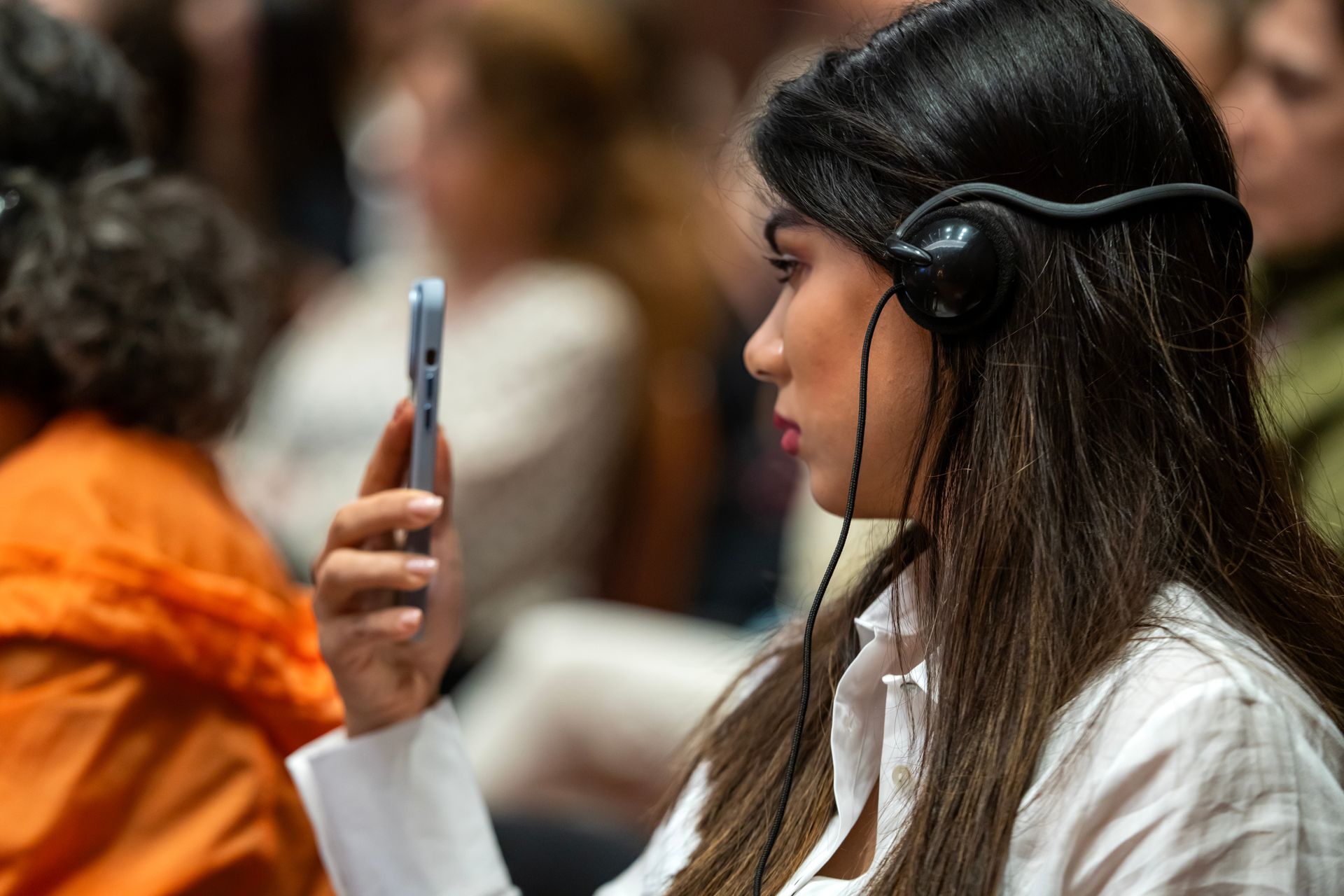Une femme portant des écouteurs regarde son téléphone portable.