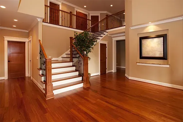 Spacious entryway with hardwood floors, staircase, and neutral walls. A framed artwork hangs on the wall.
