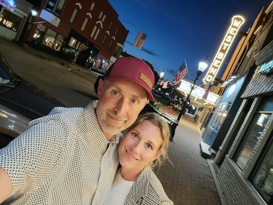 A man and a woman are posing for a picture on a city street.