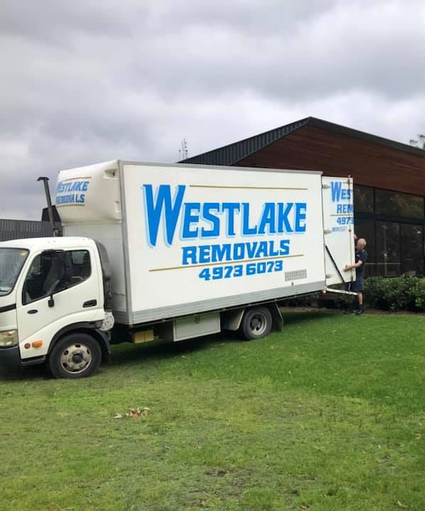 White Moving Truck from Westlake Removals Parked Next to A Building on A Grassy Lawn — Westlake Removals in Morisset, NSW