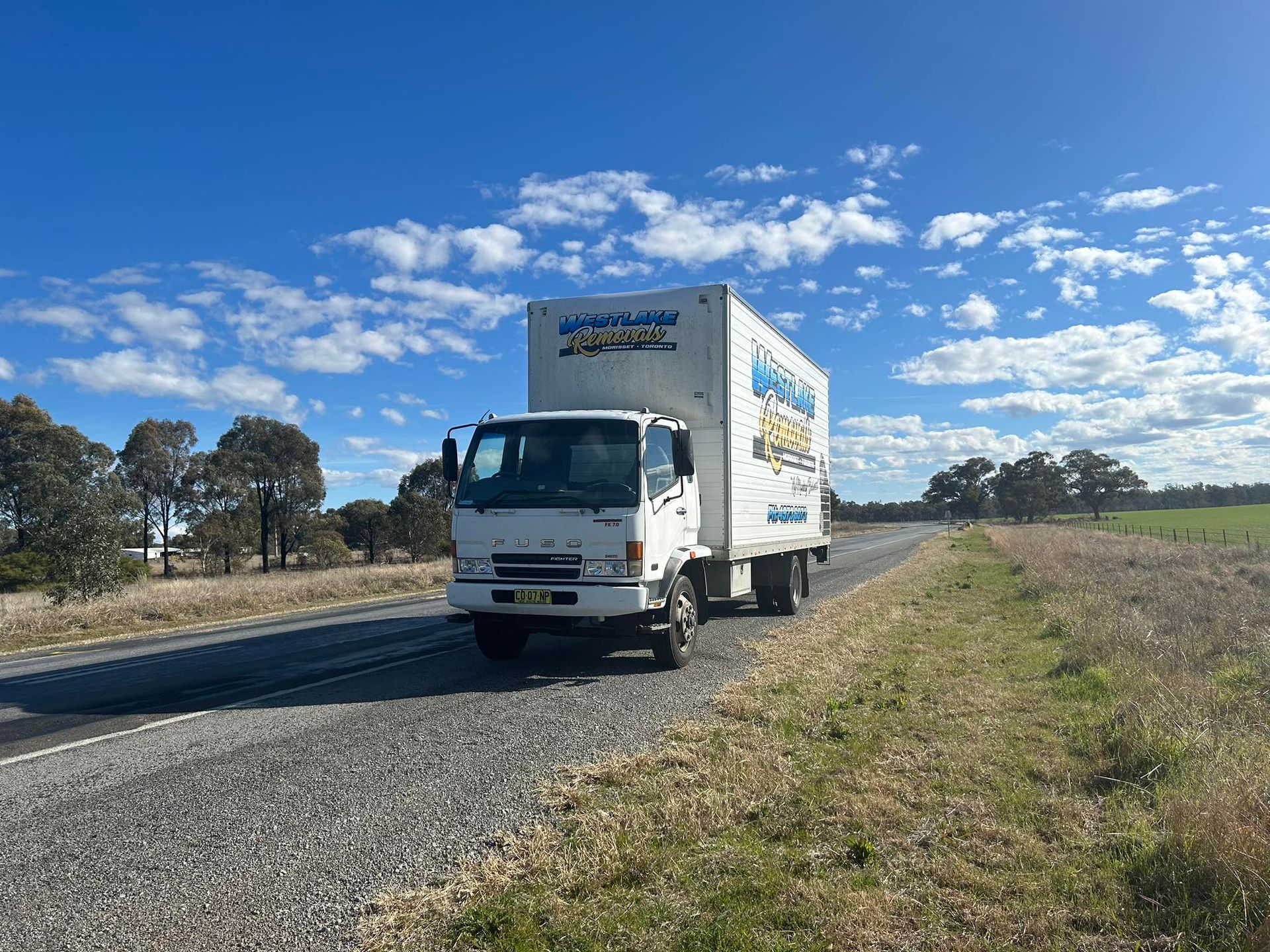 White Box Truck on A Rural Road Under a Blue Sky with Scattered Clouds — Westlake Removals in Morisset, NSW
