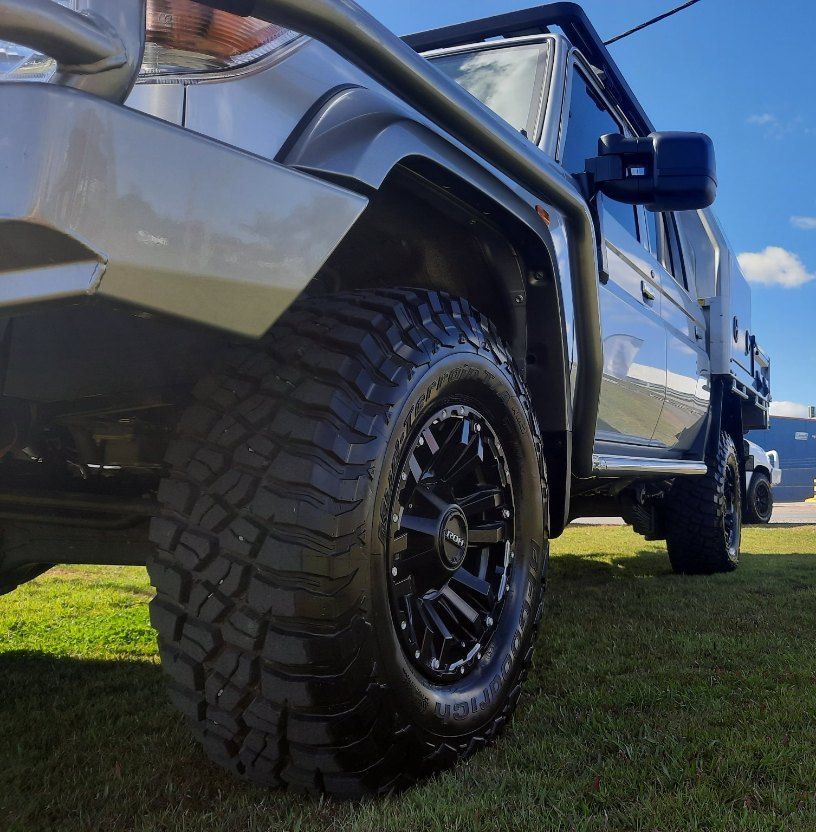 A Gray Truck Is Parked In The Grass With A Large Tire — Clarence Valley Tyre Centre in South Grafton, NSW