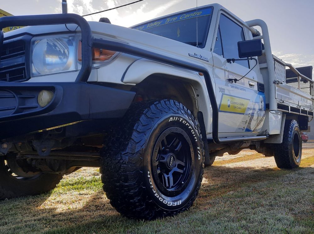 A White Truck With A Flat Bed Is Parked On A Grassy Field — Clarence Valley Tyre Centre in South Grafton, NSW