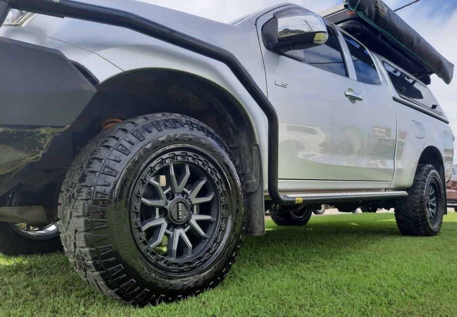 A White Truck With Black Wheels And Tires Is Parked In A Grassy Field — Clarence Valley Tyre Centre in South Grafton, NSW