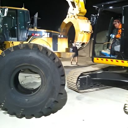 A Large Tire Sits Next To A Yellow Cat Excavator — Clarence Valley Tyre Centre in South Grafton, NSW