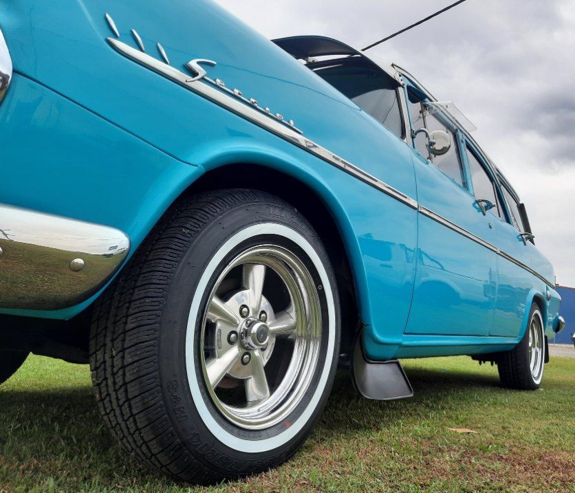 A Blue Car With White Tires Is Parked In A Grassy Field — Clarence Valley Tyre Centre in South Grafton, NSW