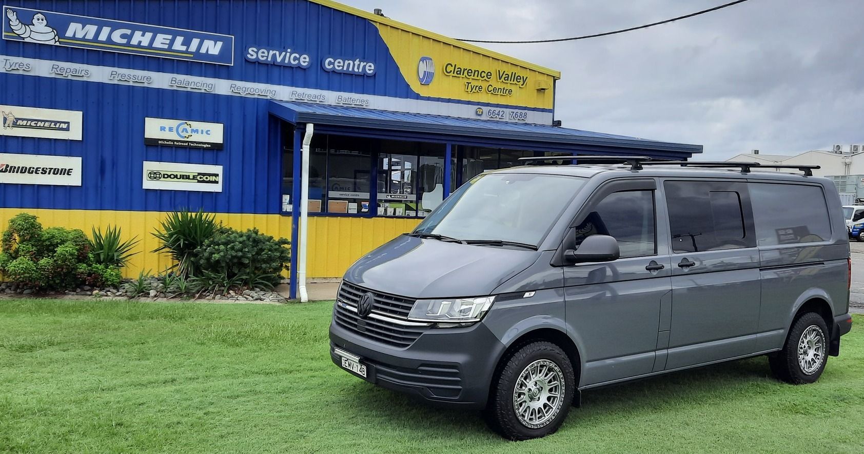 A grey van is parked in front of a blue and yellow building — Clarence Valley Tyre Centre in South Grafton, NSW