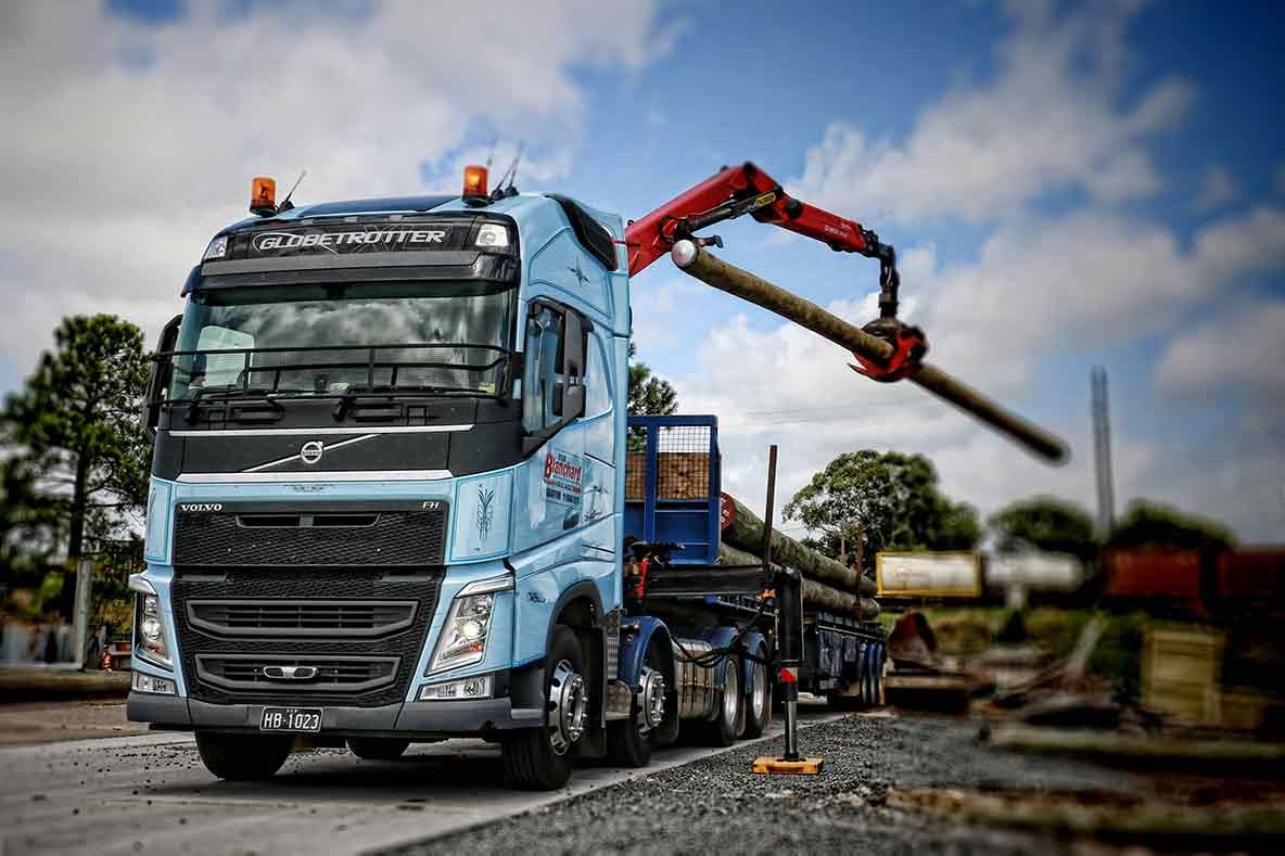A White And Blue Truck Is Parked In Front Of A Yellow And Blue Building Lifting Wood — Clarence Valley Tyre Centre in South Grafton, NSW