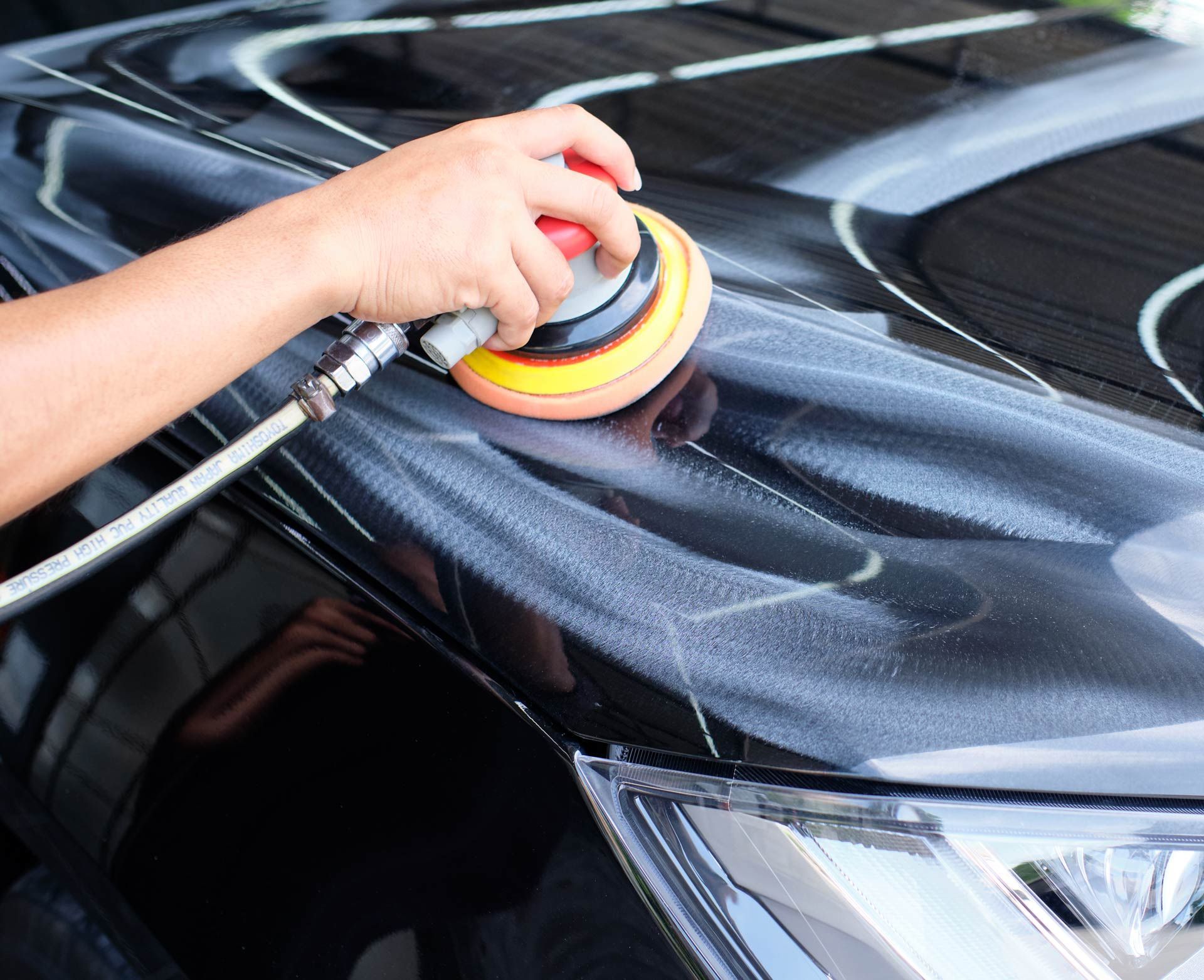 A person is polishing the hood of a black car