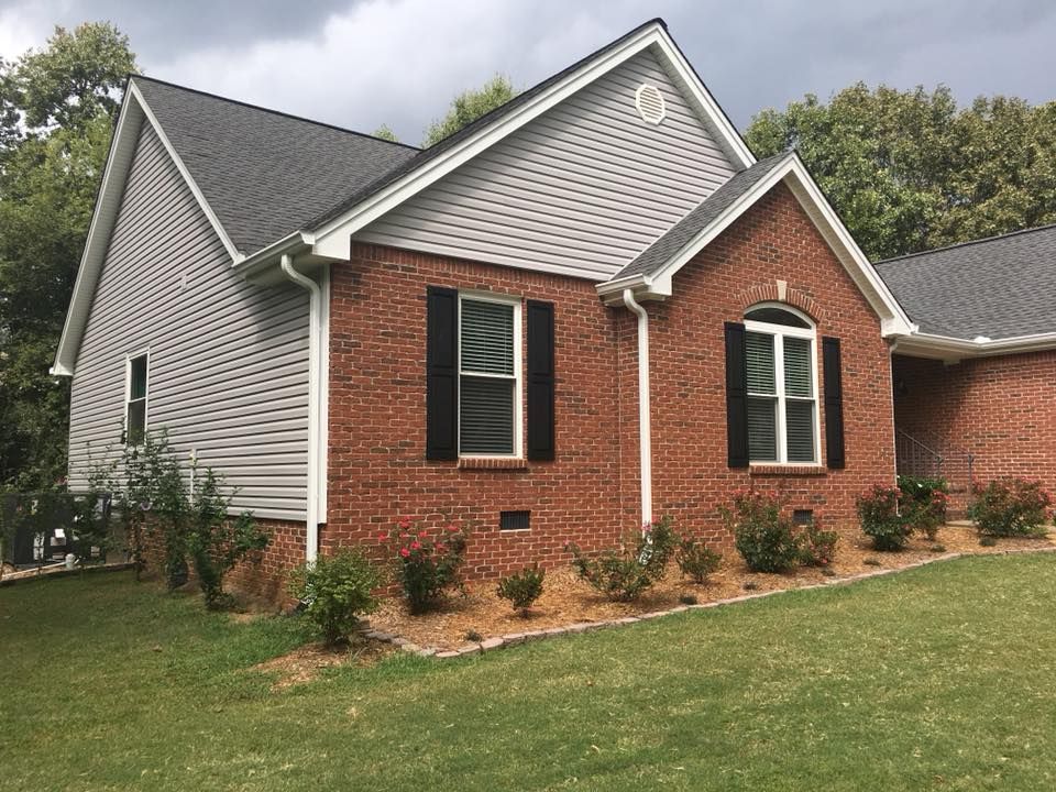 A brick house with white siding and black shutters