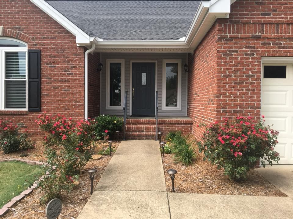 A brick house with a black door and a white garage door