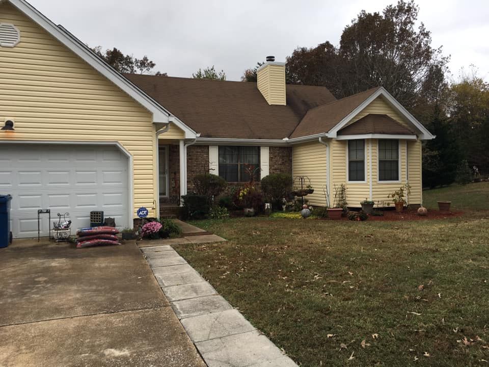A yellow house with a brown roof and a white garage door