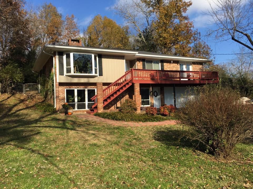 A large house with a large deck and stairs surrounded by trees.