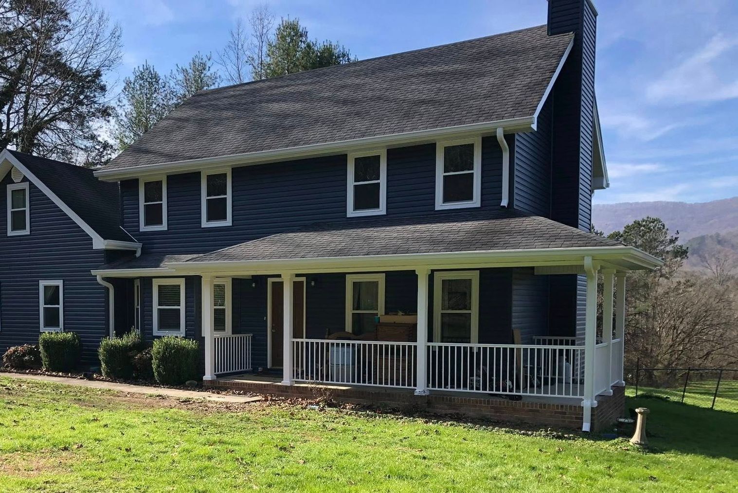 A large house with a porch and mountains in the background