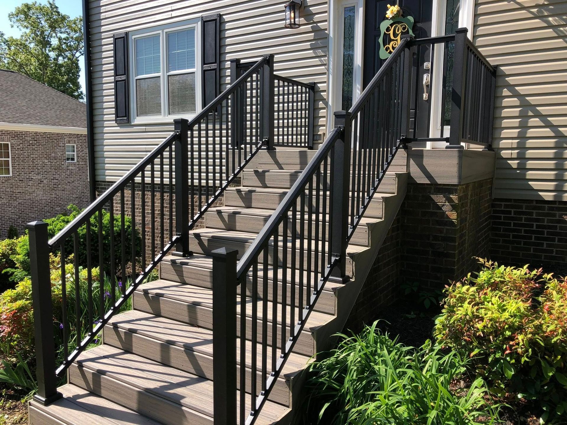 A set of stairs leading up to a house with a black railing.