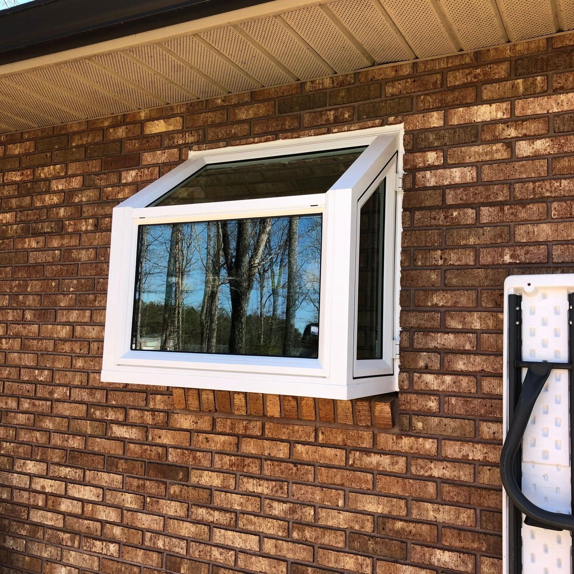 A white window is on the side of a brick building.