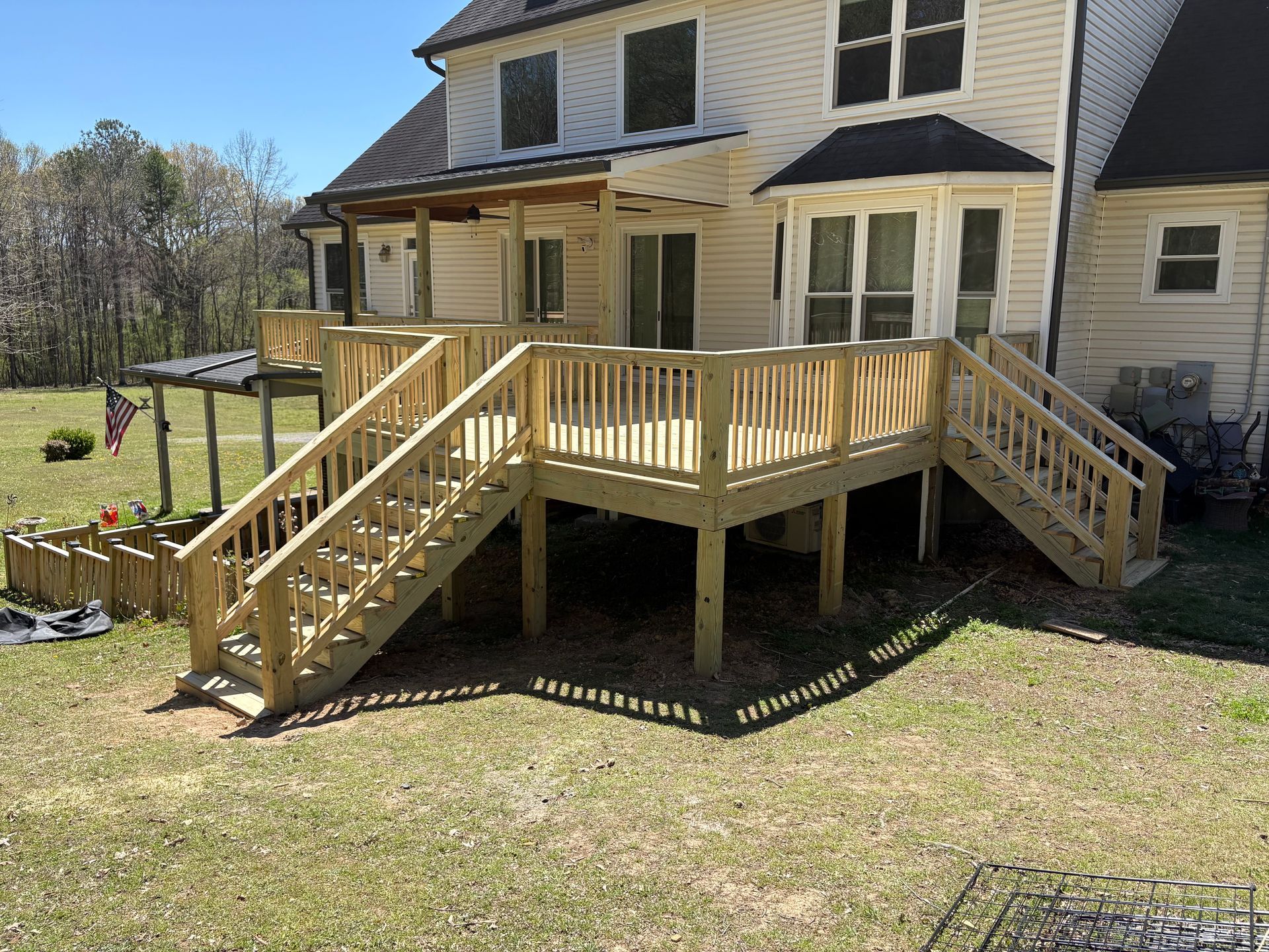 A wooden deck with stairs is in front of a house.