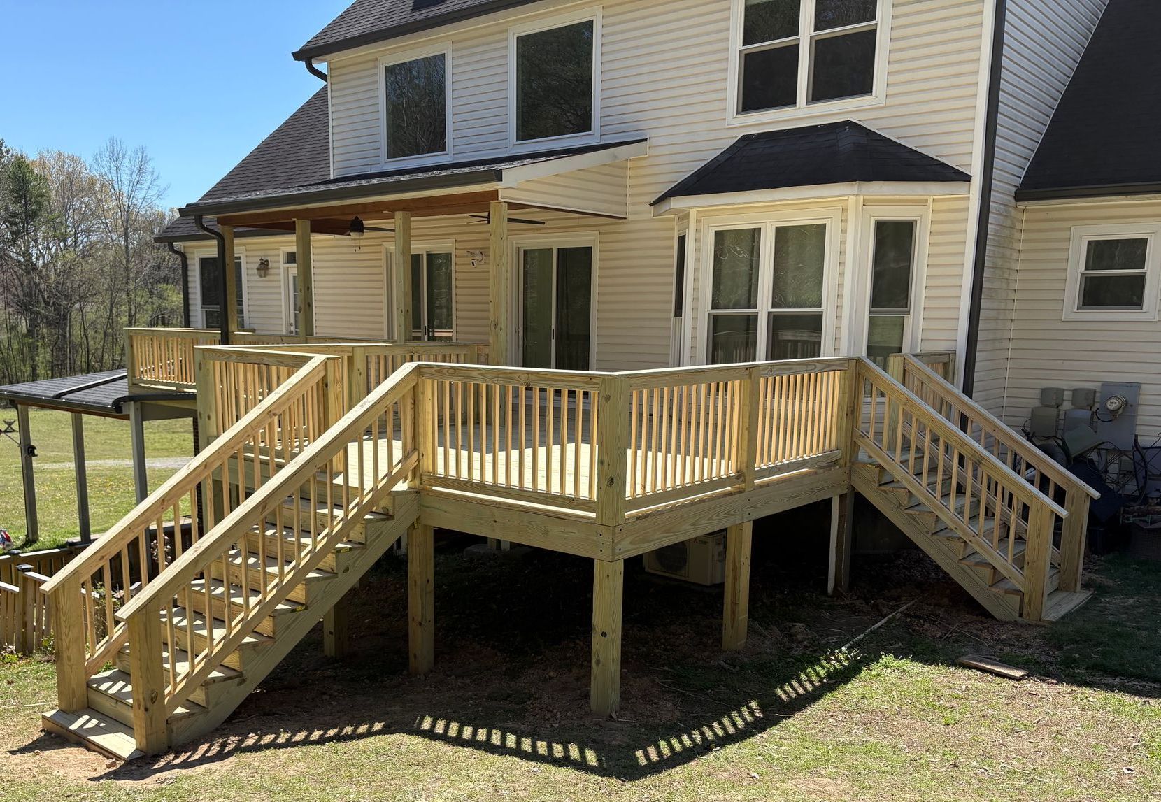 A large white house with a wooden deck and stairs in front of it.
