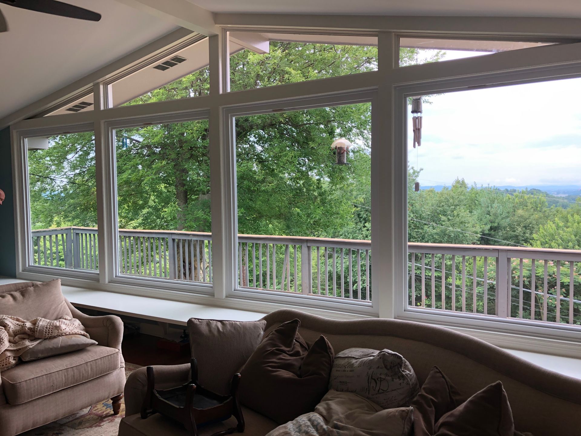 A living room with a lot of windows and a view of trees.