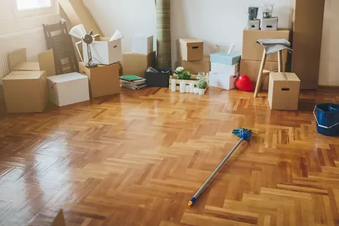 An empty room with boxes and a mop on the floor.