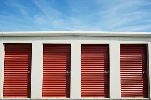 A row of red garage doors with a blue sky in the background.