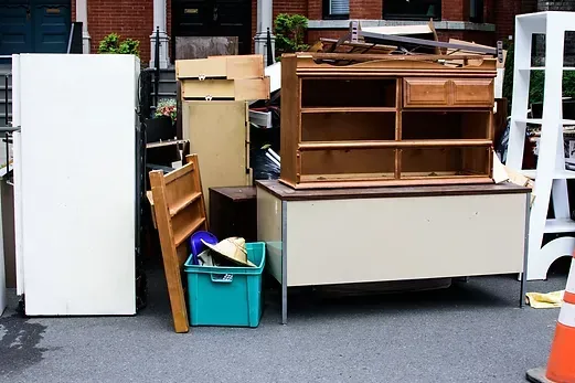 A bunch of junk is sitting on the ground in front of a building.