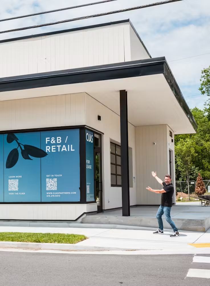 Person walking past a storefront with a blue “F&B RETAIL” window sign.