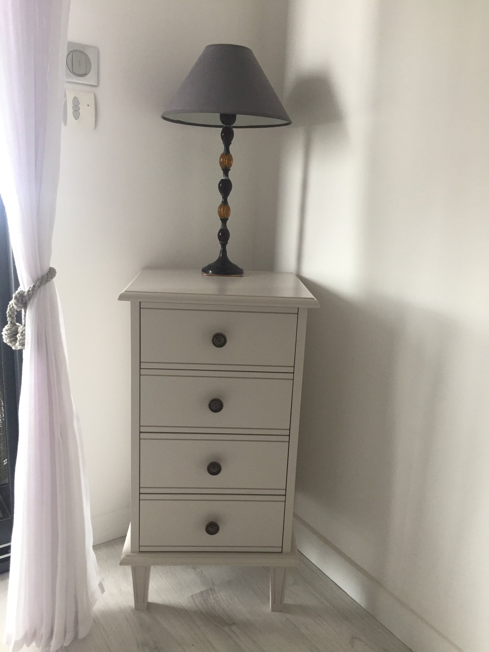 A white dresser with a lamp on top of it