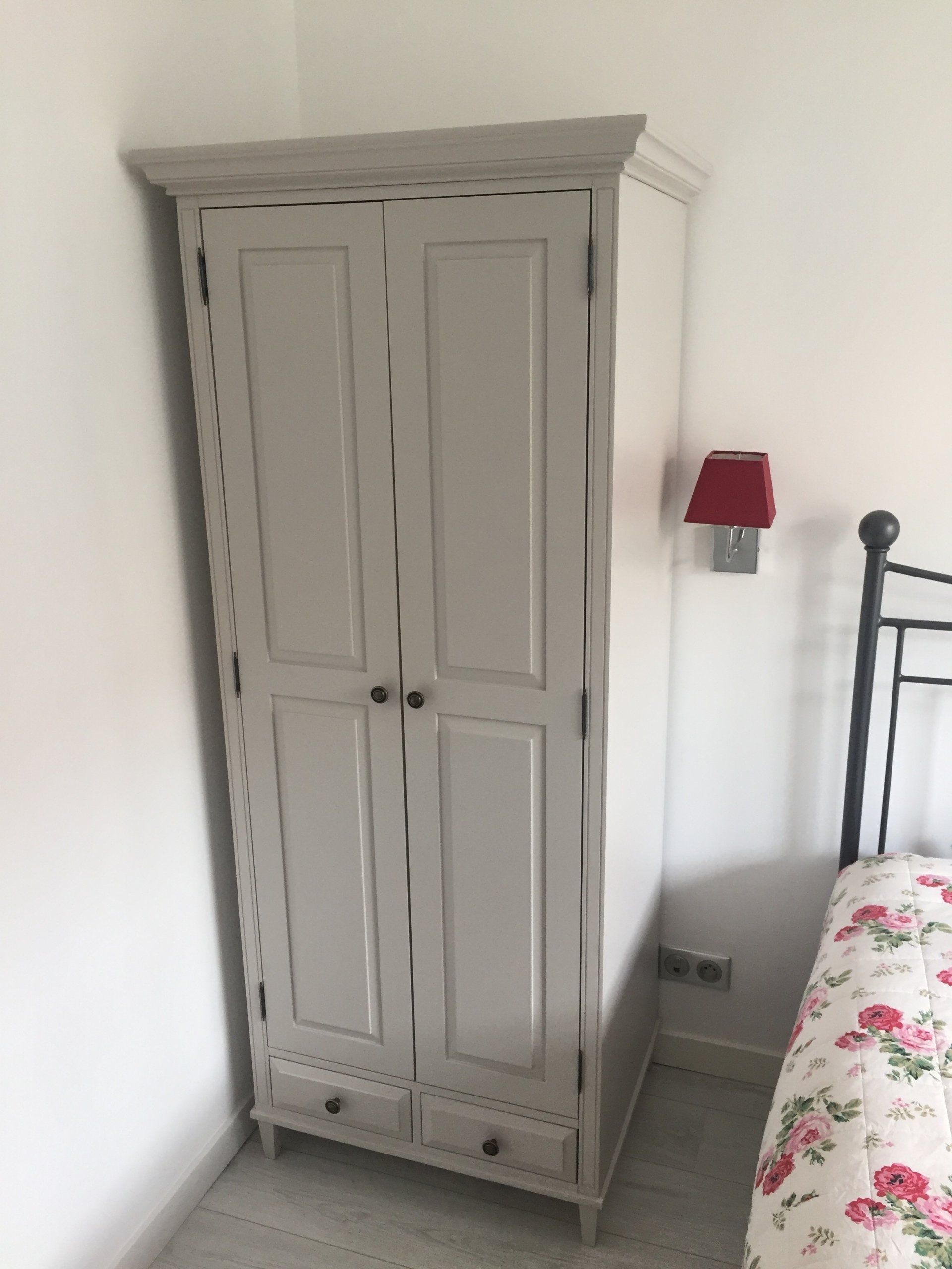 A bedroom with a wardrobe and a lamp on the wall