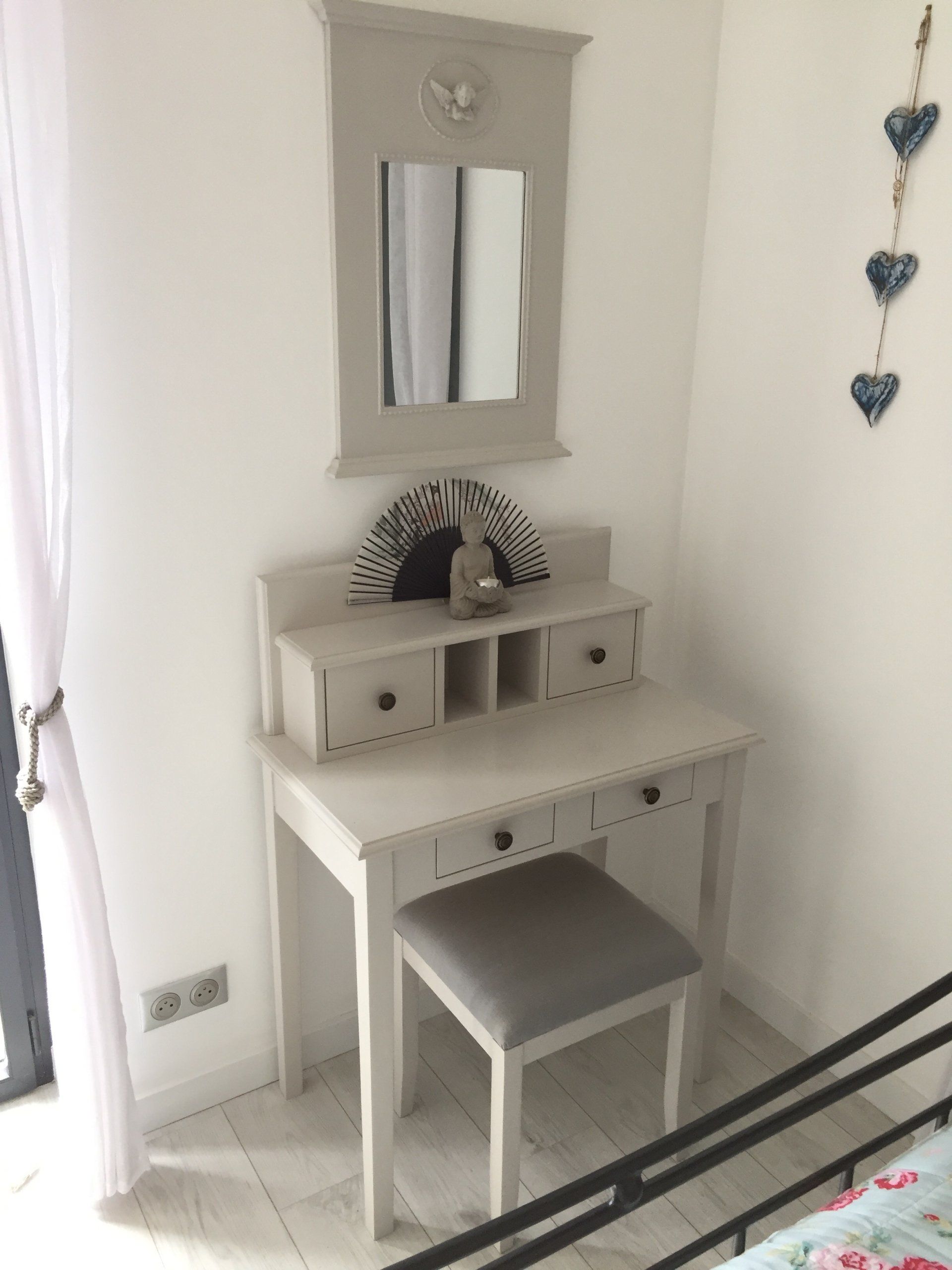 A vanity with a mirror and a stool in a bedroom next to a bed.
