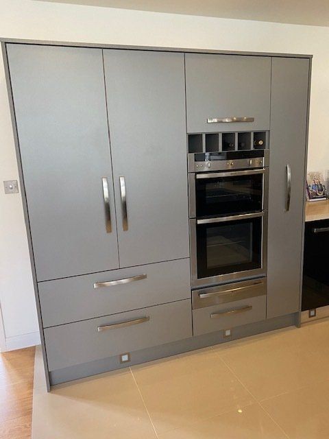 A kitchen with gray cabinets and drawers and a stainless steel oven.