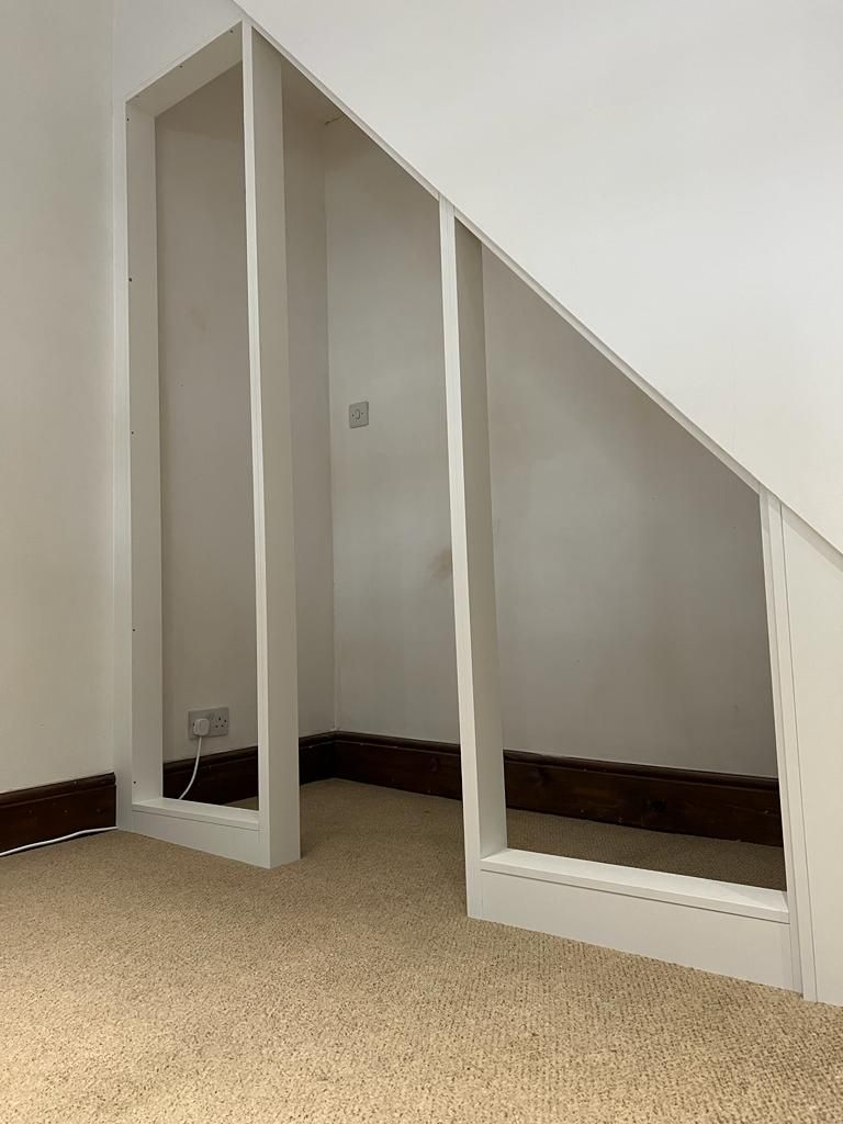 A room with a slanted ceiling and a carpeted floor.